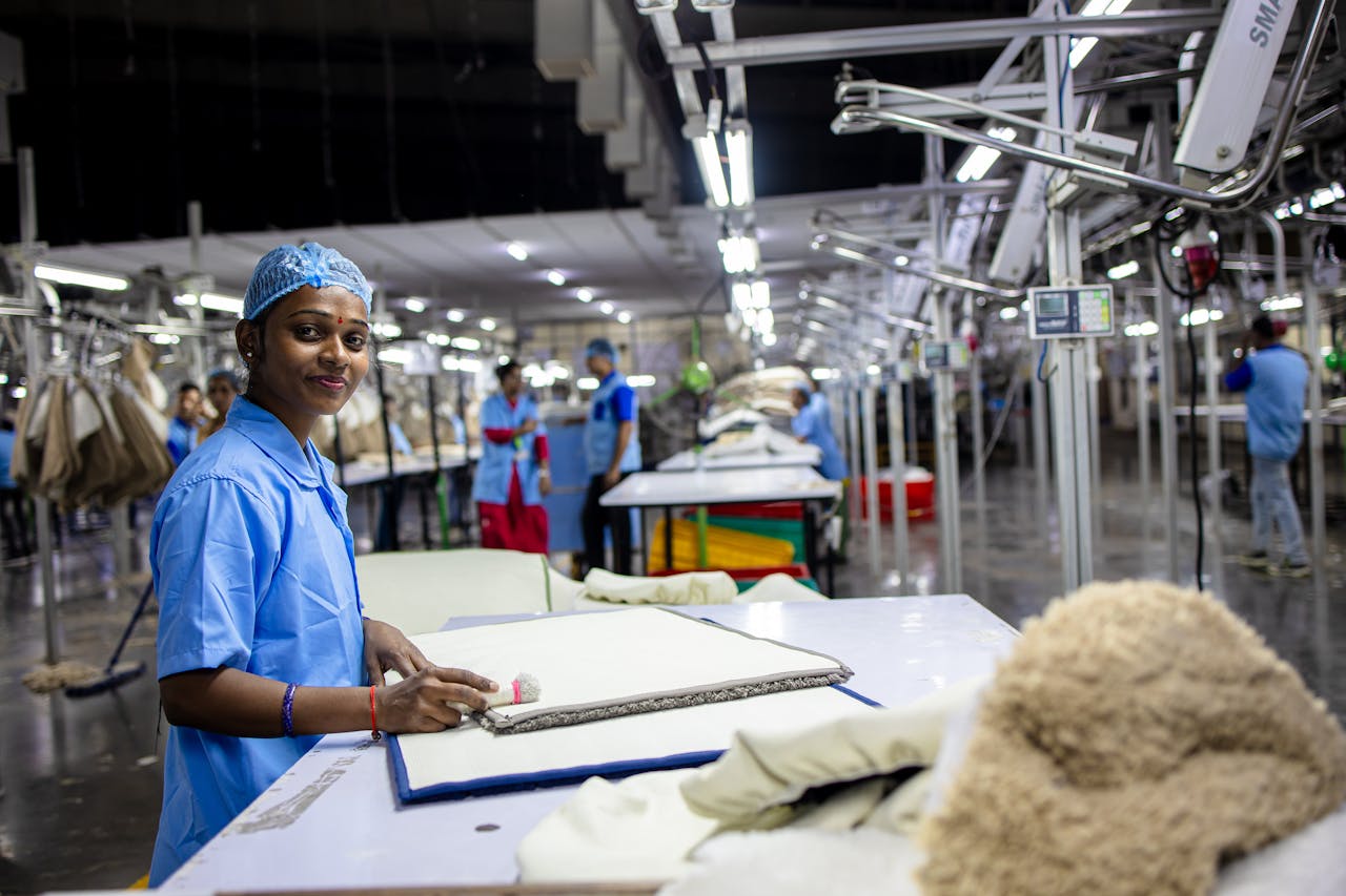 Textile factory workers engaged in production, wearing blue uniforms in a modern and well-lit environment.